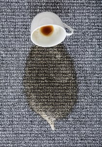 Coffee spill on a carpeted floor representing the spot and spill removal service of difficult stain removals offered by Flexgreen.