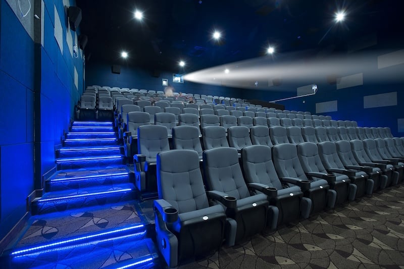 A movie theater room in North Carolina with upholstered chairs and carpet.